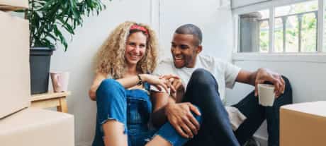 couple sat on floor smiling in new house 
