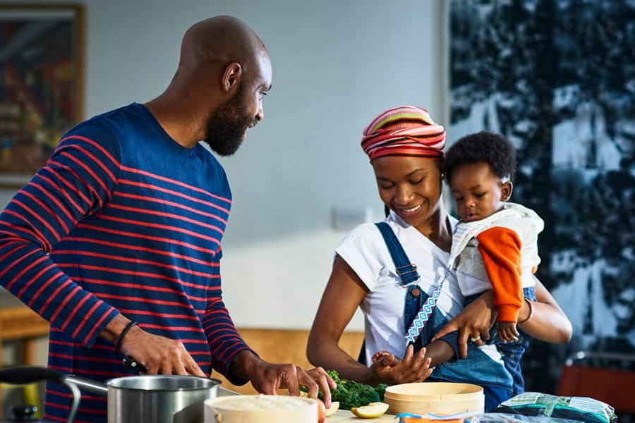 Couple with a baby making food.