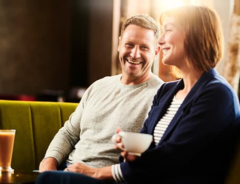Man looking at woman laughing drinking coffee