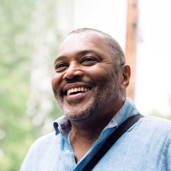 a man outside smiling with a shoulder bag