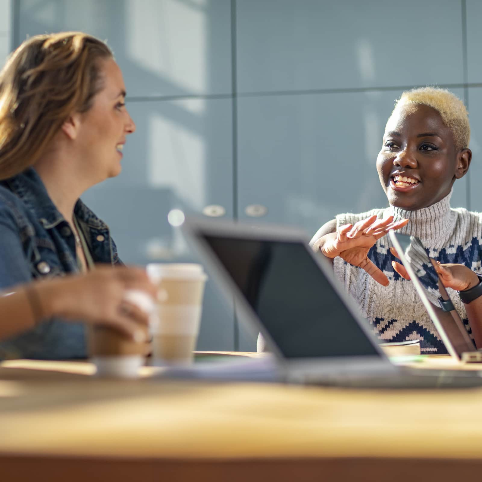 Two women talking at a table with coffee