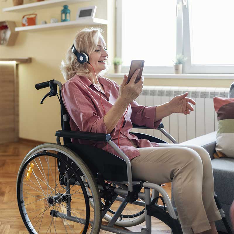 A woman in a wheelchair using a phone with headphones