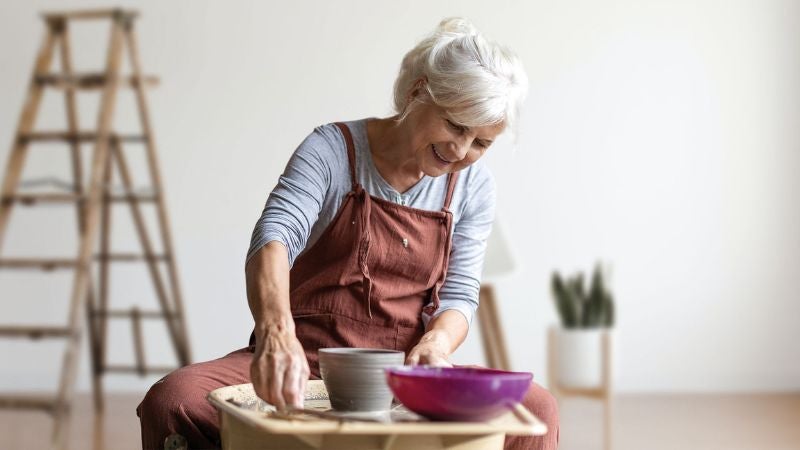 Woman making a bowl at a pottery wheel.