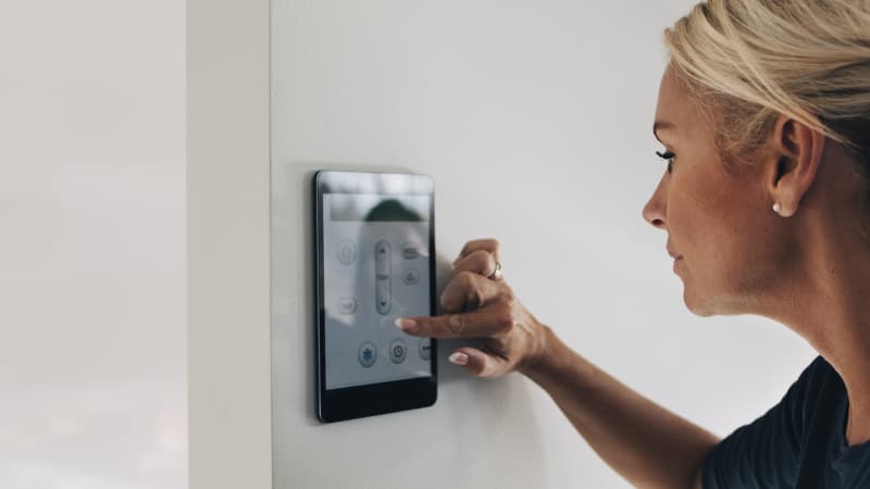 Woman adjusting digital house thermostat