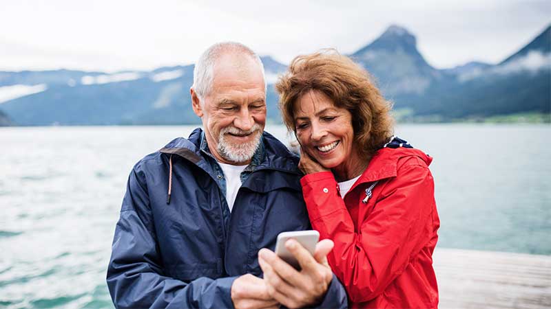 older couple stood together looking at phone