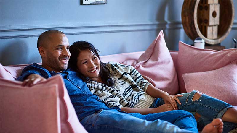 Couple sat on couch with feet up 