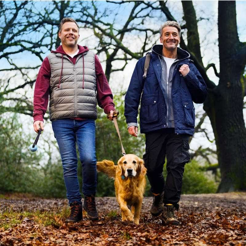 Two men walking a dog in the woods