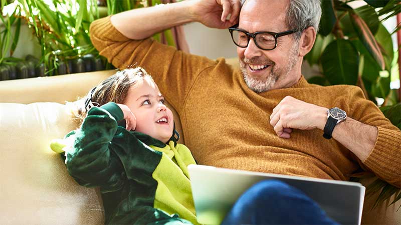 man and child sat on sofa smiling at each other