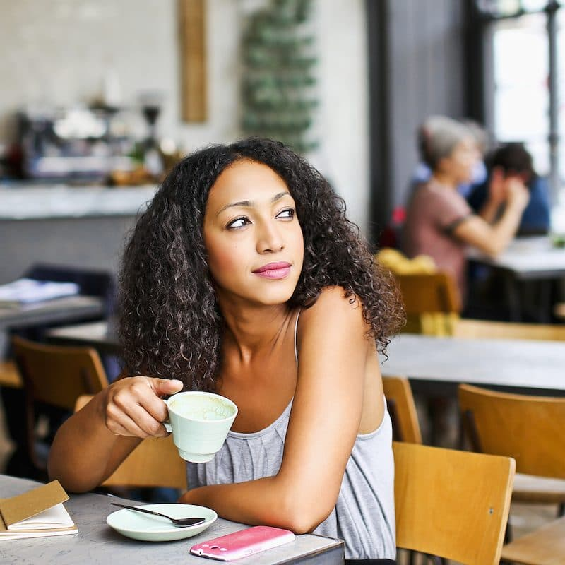 Young woman holding a tea cup, in a coffee shop