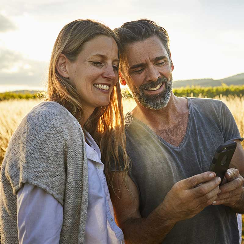 Older couple looking at a phone together, in a garden