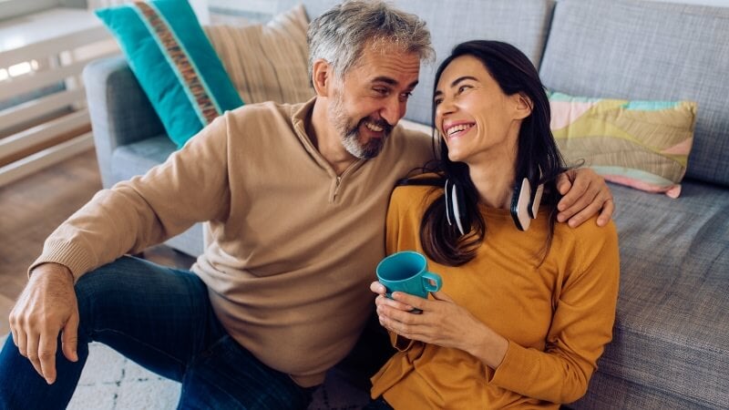 Couple sat on floor smiling at each other