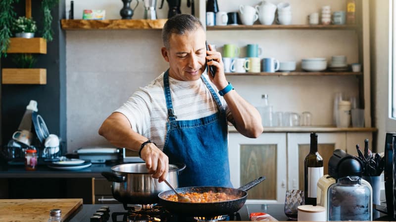 Man in kitchen on the phone while cooking 