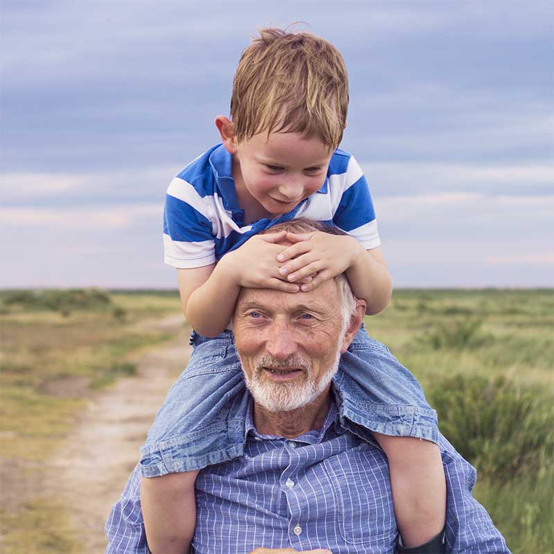 Retired man giving a piggy back to a young boy