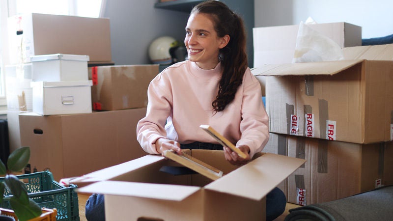 Smiling young woman unpacking boxes